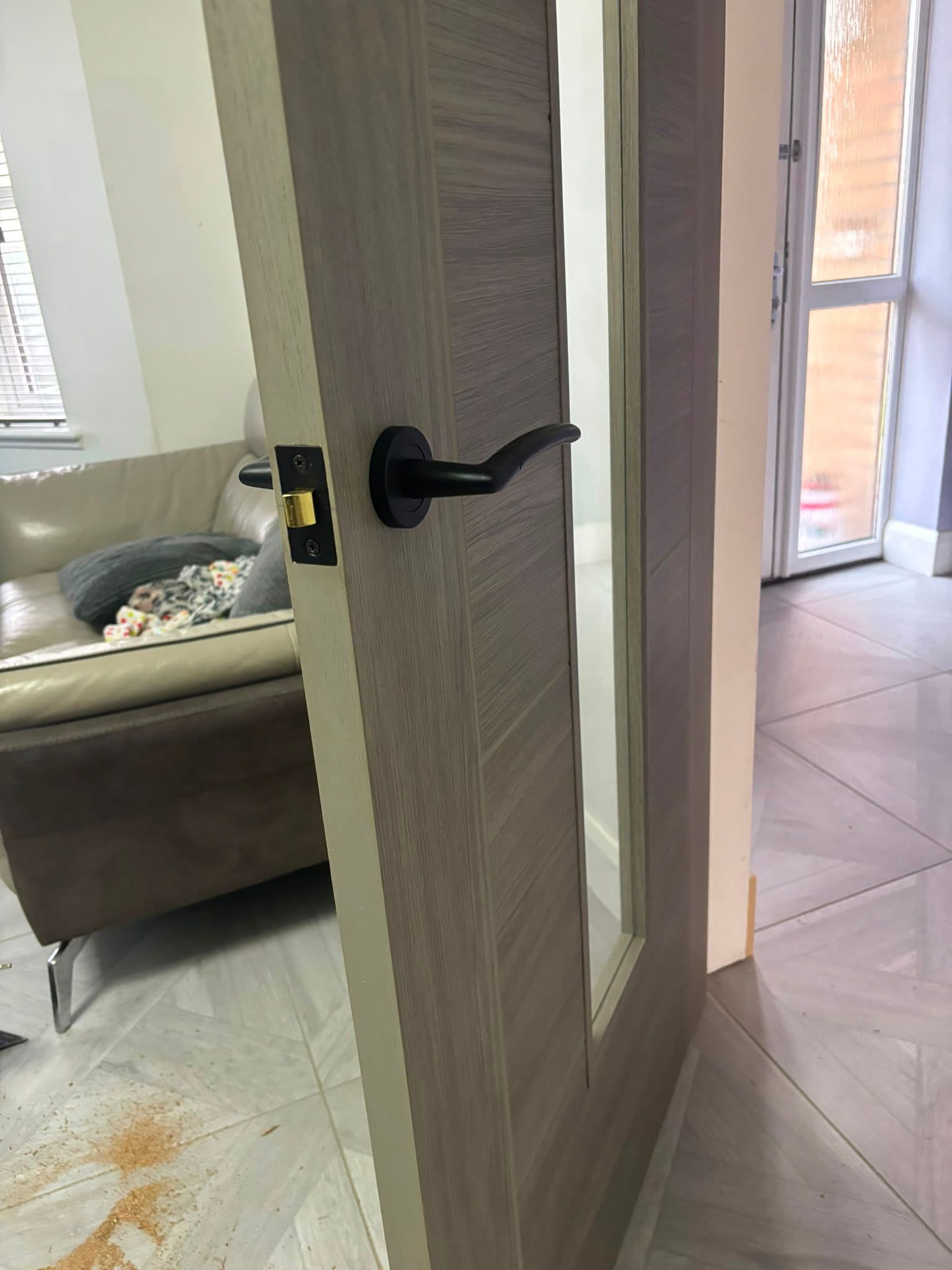 Black lever door handle on a grey woodgrain internal door