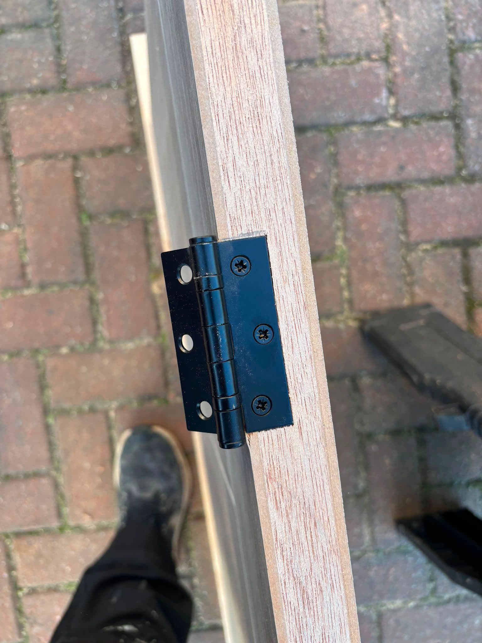 Close-up of a black hinge being fitted to a new internal door