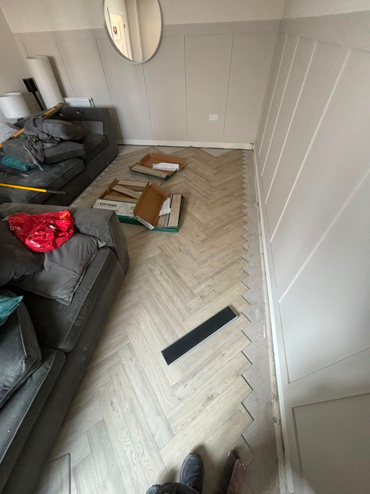 Light grey herringbone LVT flooring being laid in a living room